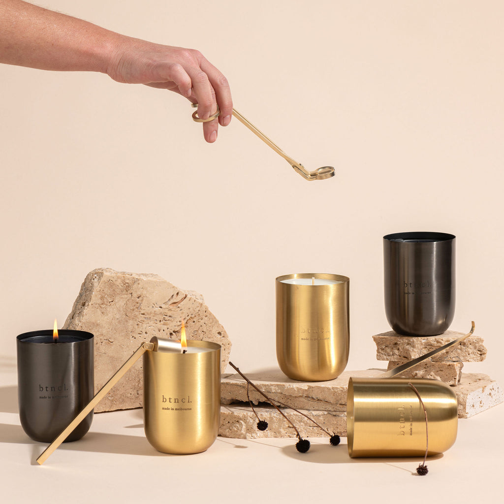 Brass and black vessel candles on travertine slabs with candle accessories