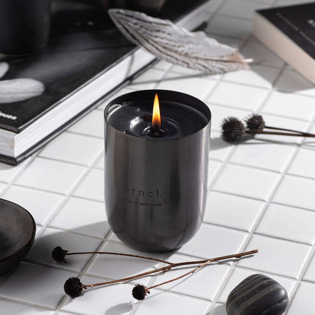 black candle on white tiles with books