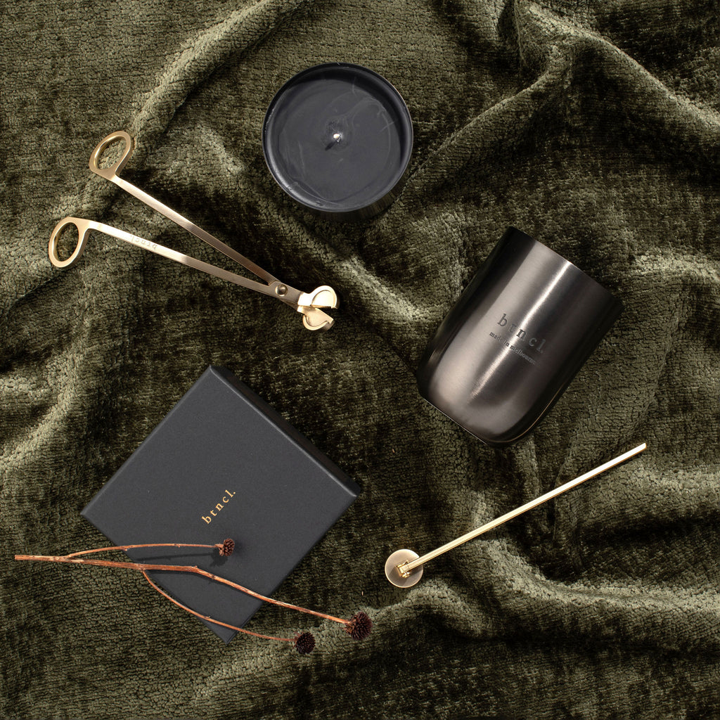 Black candle on green velvet with candle accessories