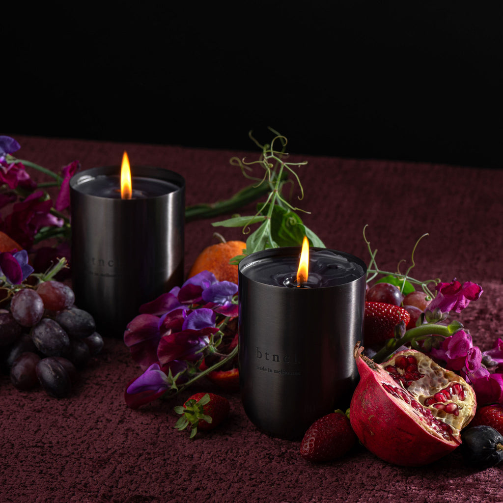 btncl brass candle on dark velvet with fresh florals and grapes