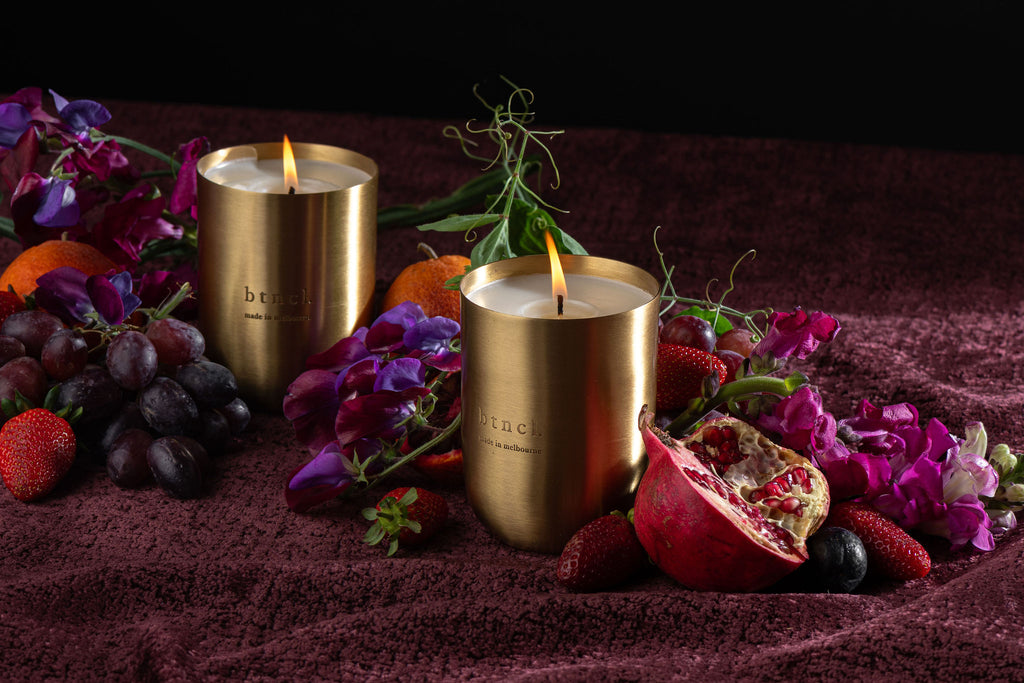 btncl brass candle on dark velvet with fresh florals and grapes