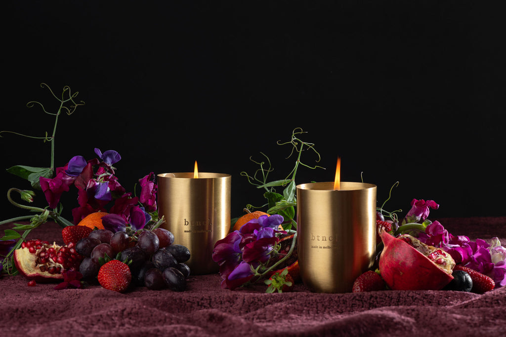 btncl brass candle on dark velvet with fresh florals and grapes