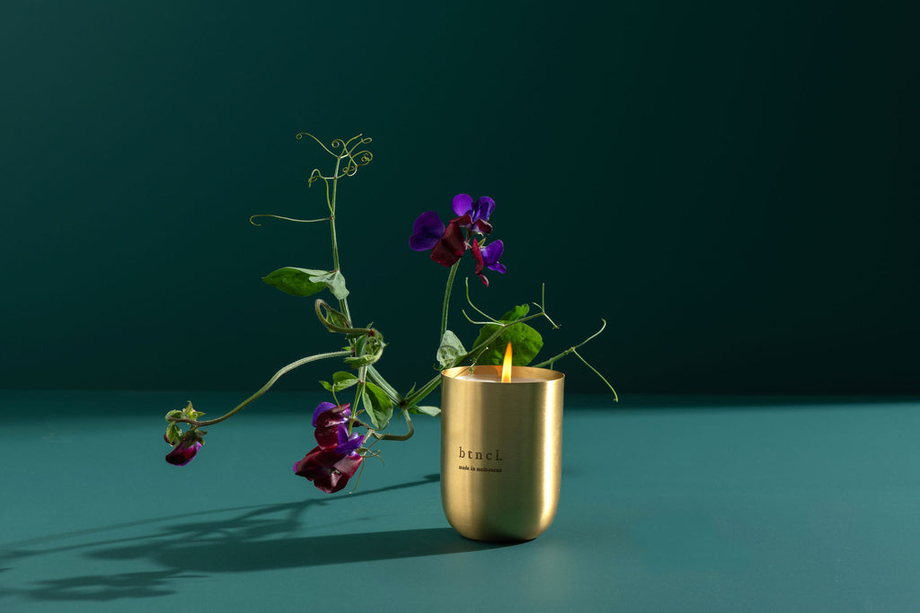 Brass candle on teal background with fresh florals