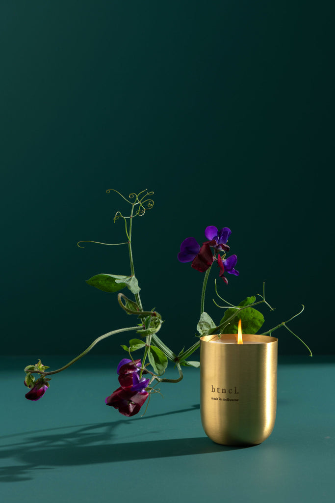 Brass candle on teal background with fresh florals