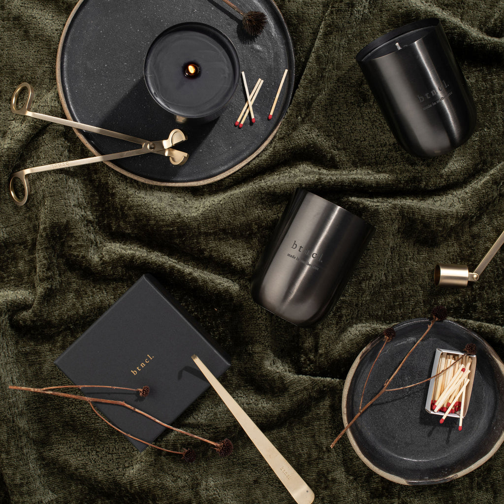 Candle care tools and black candles on warm dark backdrop