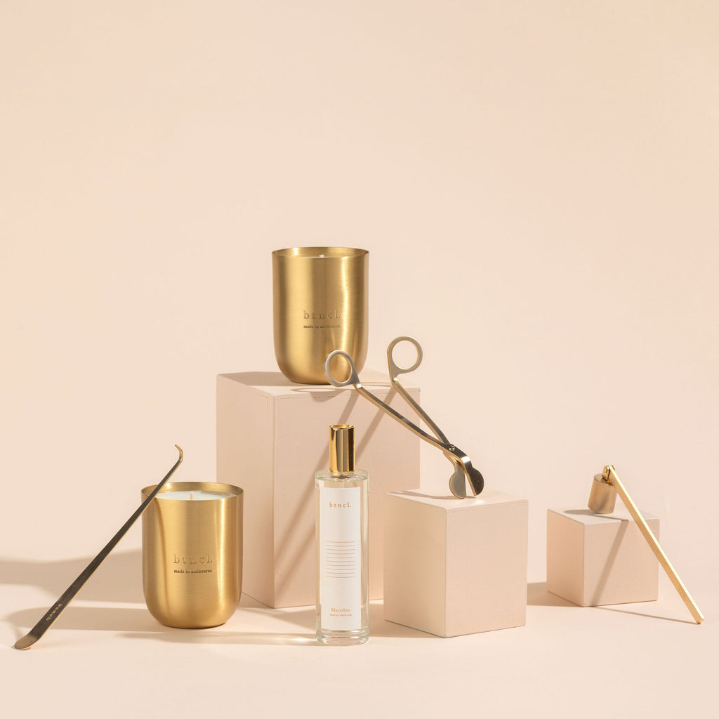 Brass candle and perfume with candle accessories on neutral plinths