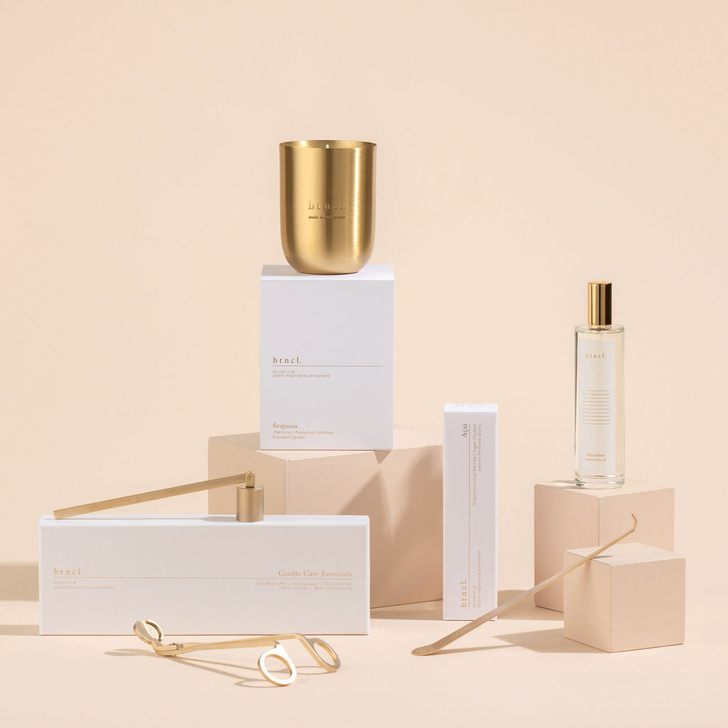 Black candle and perfume with candle accessories on neutral plinths