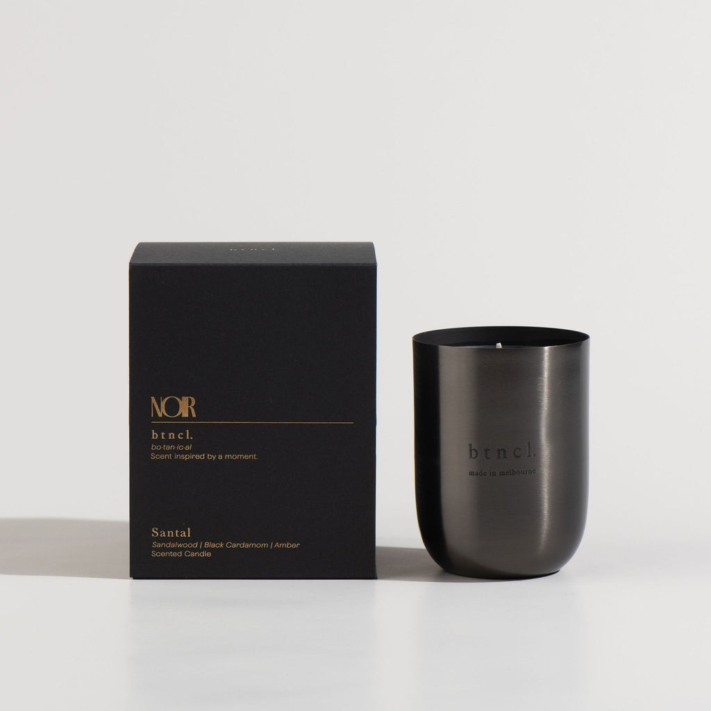 black santal candle next to black packaging