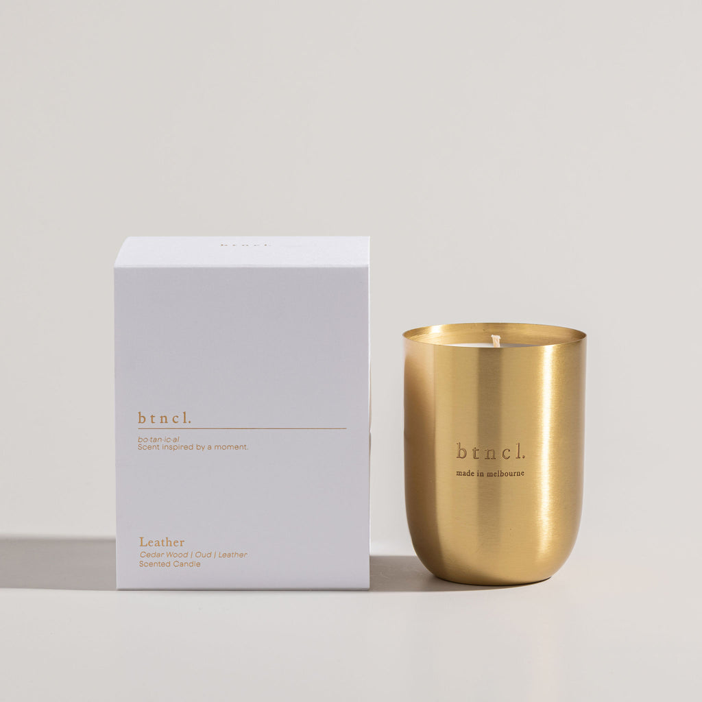 Leather candle in brass next to white packaging